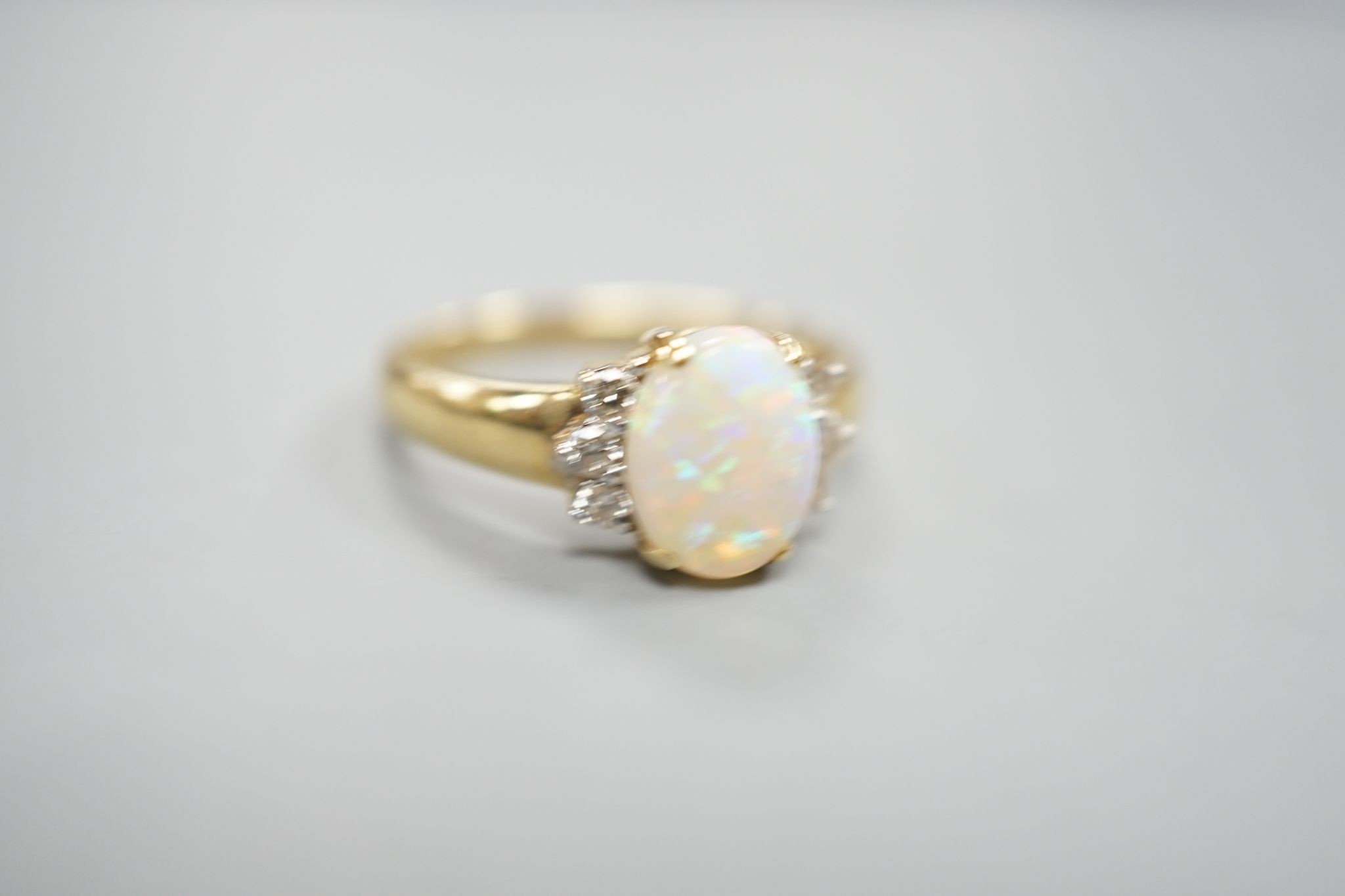 A modern 14k yellow metal, oval white opal and six stone diamond set cluster ring, size N, gross weight 2.9 grams.